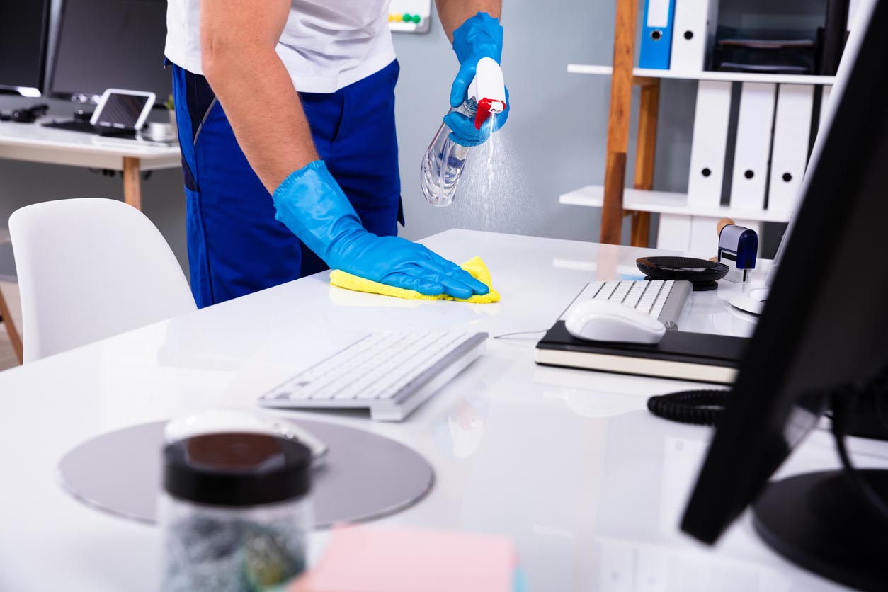 Man cleaning white desk in office